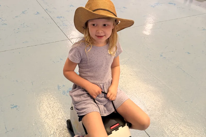Kid riding a rolling suitcase in the cruise terminal