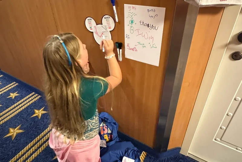 Child writing on magnetic dry erase boards on a cabin door